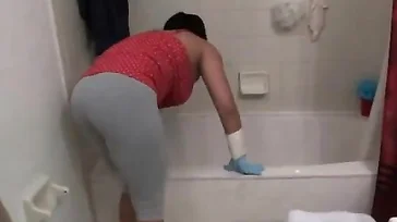 A senhora faz um show para limpar a banheira.